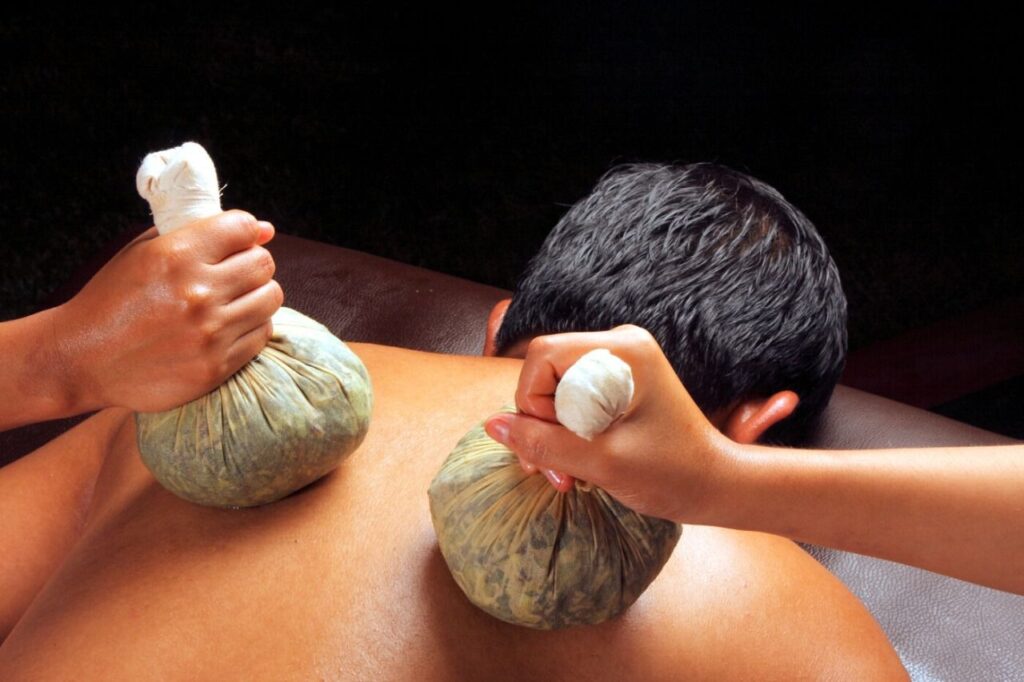 A man receiving Elakizhi therapy, with herbal compresses applied to the body to alleviate muscle tension and promote relaxation