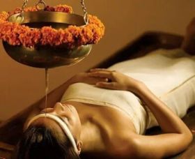 A person experiencing Takradhara therapy, with herbal decoctions gently poured over the body for relaxation and rejuvenation