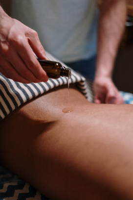 An Ayurvedic therapist preparing herbal medicines while a woman relaxes during a back massage at Jivika Wellness Spa