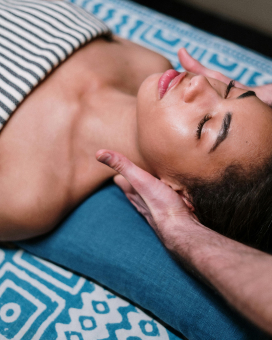 An Ayurvedic therapist preparing herbal medicines while a woman relaxes during a head massage at Jivika Wellness Centre